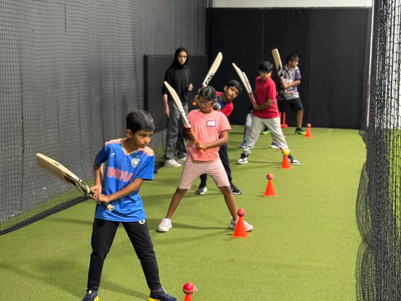 Kids lined up with bats at the Calgary Cricket Centre, practising their stance over cones